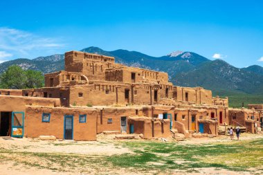 TAOS, NEW MEXICO, USA - JUNE 25, 2019: Tourists visit  the historic Taos Pueblo. clipart