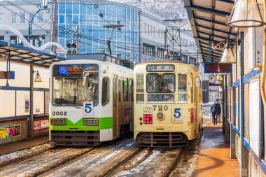 HAKODATE, JAPAN -  FEBRUARY 4, 2017: A passenger alights from the tram. It originates from 1897 and is a local landmark as well as an efficient means of transit. clipart