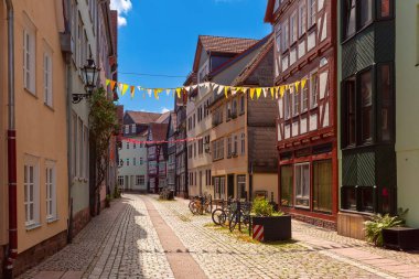 Traditional timber-framed houses line the cobblestone street leading to Marburg Castle, Germany clipart