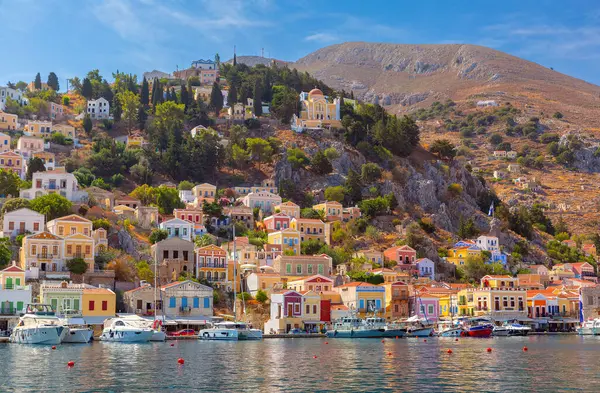 stock image Hillside view of the colorful buildings and busy harbor on Symi Island, Greece.