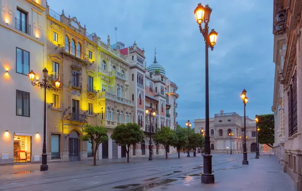 stock image Old houses on Constitution Avenue in the light of lanterns at dawn, Seville, Andalusia, Spain