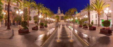 Night view of San Juan de Dios Square with illuminated palm trees and the Town Hall in Cadiz, Spain clipart