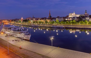 Illuminated night view of the Szczecin riverfront along the Oder River in Poland clipart