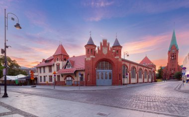 View of the historic Old Fire Station and St. Andrew Bobola Church at sunrise in Bydgoszcz, Poland, with empty streets and cobblestone pavement. clipart