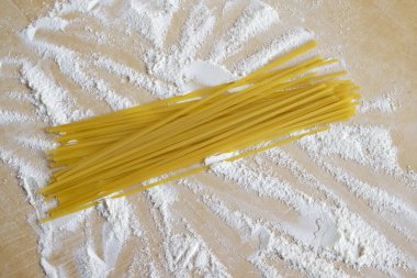 Hamur tahtasındaki un ile çiğ spagetti.