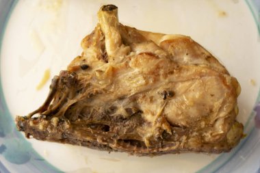 Kalçaları üzerinde fırında tavuk, beyaz bir tabakta.