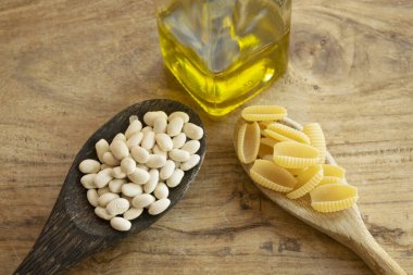 iki tahta kaşıkta malzemeli makarna ve fasulye.