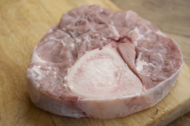 raw slices of ossobuco on a wooden cutting board