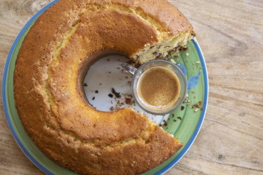 Ortasında bir fincan kahve olan yuvarlak donut.