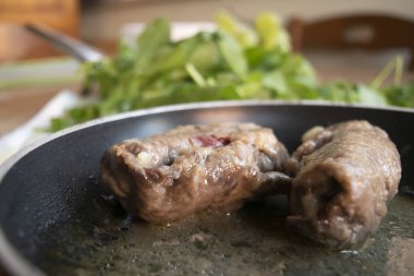Bir tavada pişmiş et Roulade ve bir kapağın üzerinde sergilenir.