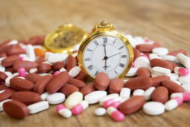 Bir yığın hap ve eski cep saati olan zaman ve sağlık kavramı