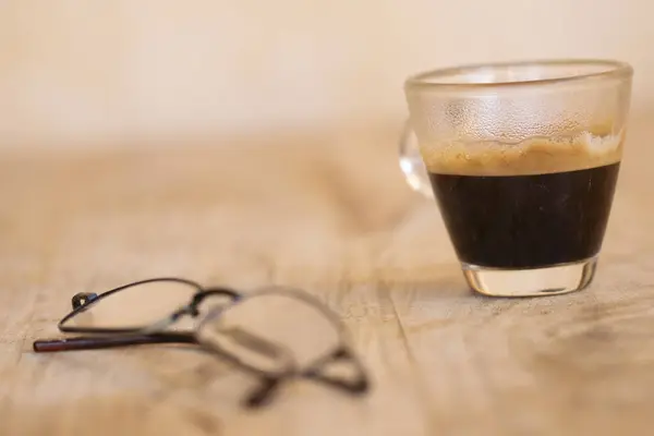 espresso coffee in a glass cup with the glasses  in the foreground