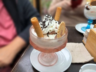 Kremalı ve gözlemeli cam bardakta çikolatalı dondurma.