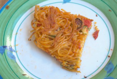Beyaz tabakta bir dilim omlet makarna.
