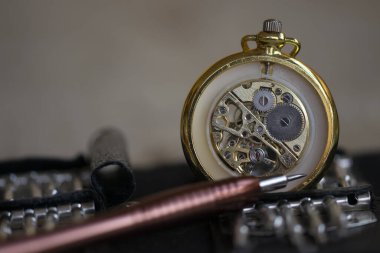 Ön planda bir cep saati ve hassas tornavida dişlileri