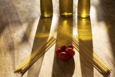 Zeytinyağı ve taze domatesli spagetti ışığın yansımaları üzerine.