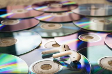 Masaya yayılmış eski CD 'ler. Üstünde de kablosuz kulaklık var.