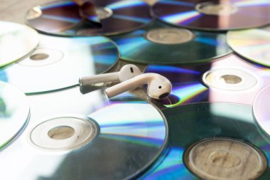 Masaya yayılmış eski CD 'ler. Üstünde de kablosuz kulaklık var.