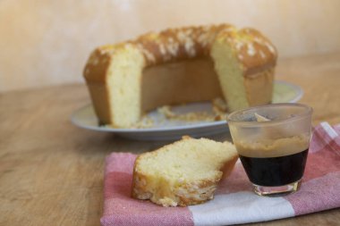 Cam bardakta espresso ve limonlu çörek dilimi.