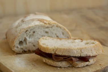Ekmek dilimleri ve çiğ jambonla yapılmış sandviç.