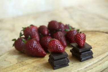 Olgun çilekler arasında bir yığın çikolata karesi