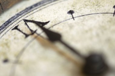 Bir duvar saatinin üzerindeki saat kolunun yakın çekimi, zamanın geçişini ve kısacık anları sembolize eder.