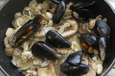 Karides, midye ve istiridye içeren geleneksel bir İtalyan makarna tabağı, ahşap bir masada kırsal seramik bir kasede servis edilir, gurme yemeği için mükemmeldir.