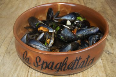 Lezzetli bir deniz ürünleri karışımı midye, istiridye ve karides ahşap bir masada servis edilen rustik kil kasesinde, gurme yemek için mükemmel.