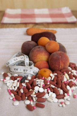 Diyet ve sağlık hizmetleri için doğal gıda ve haplar arasında seçim yapmak, ölçüm bandı, elma ve havuç ile