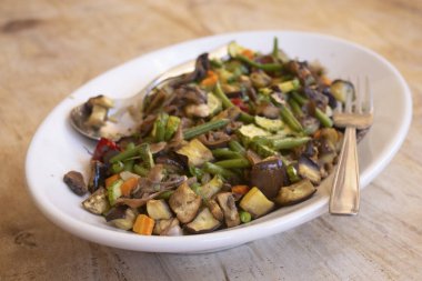 Sağlıklı ve renkli bir tabak sotelenmiş sebze ve kabarık beyaz pirinç kırsal ahşap bir masada servis edilmeye hazır.