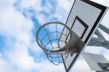 Street basketball hoop, net and board against the background of the blue sky and clouds