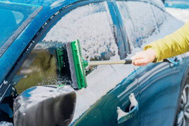 Kış araba bakımı bir aracın camından karı kaldırıyor