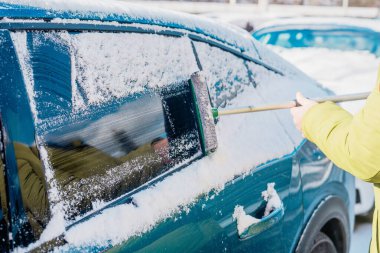 Kış araba bakımı bir aracın camından karı kaldırıyor