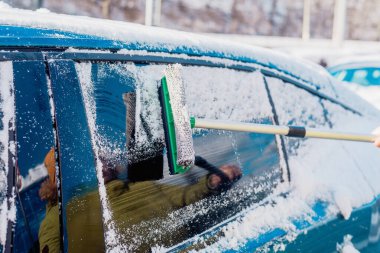 Kış araba bakımı bir aracın camından karı kaldırıyor