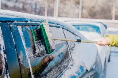 Kış araba bakımı bir aracın camından karı kaldırıyor