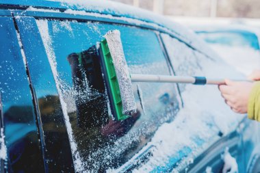 Kış araba bakımı bir aracın camından karı kaldırıyor