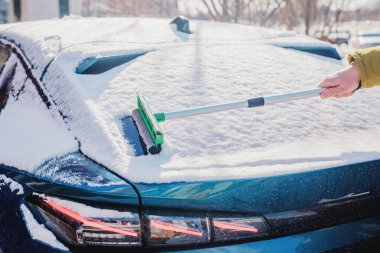 Kış araba bakımı bir aracın camından karı kaldırıyor