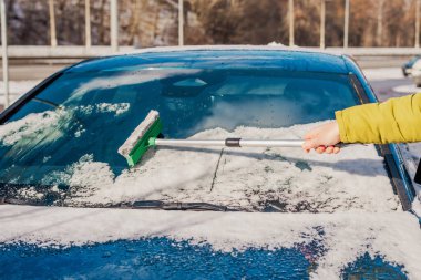 Kış araba bakımı bir aracın camından karı kaldırıyor