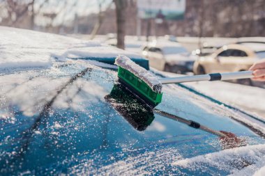 Kış araba bakımı bir aracın camından karı kaldırıyor