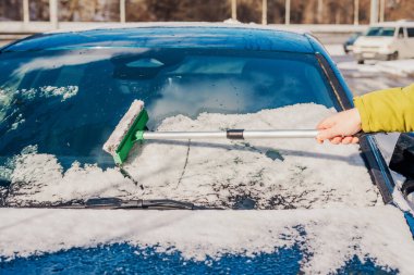 Kış araba bakımı bir aracın camından karı kaldırıyor