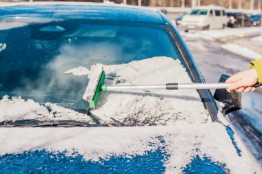 Kış araba bakımı bir aracın camından karı kaldırıyor
