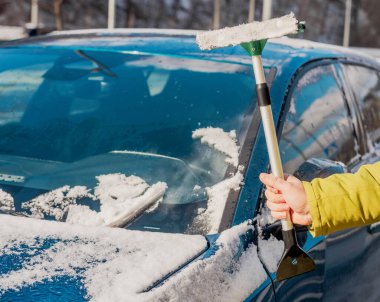 Kış araba bakımı bir aracın camından karı kaldırıyor