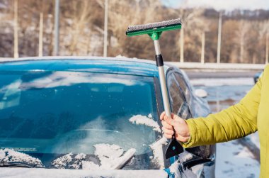 Kış araba bakımı bir aracın camından karı kaldırıyor