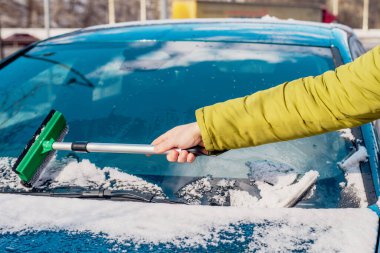 Kış araba bakımı bir aracın camından karı kaldırıyor