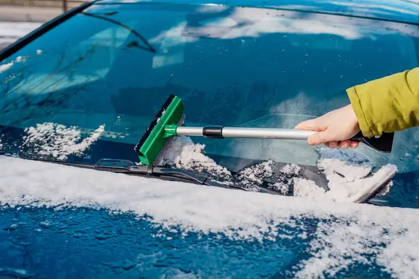Kış araba bakımı bir aracın camından karı kaldırıyor