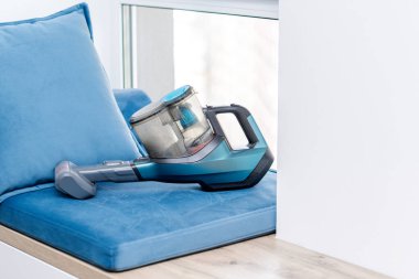 Pencerenin yanındaki oturma yerinde yastıklı elektrik süpürgesi var.