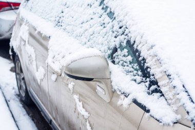 Bir fırçayla arabadan karı temizliyorum.