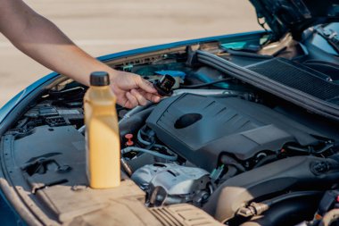 Bir arabanın motoruna motor yağı döken birinin yakın çekimi. Araç bakımı, yağ değişimi, otomotiv bakımı ve araba servisi kavramı.
