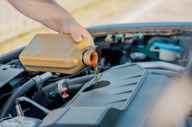 Bir arabanın motoruna motor yağı döken birinin yakın çekimi. Araç bakımı, yağ değişimi, otomotiv bakımı ve araba servisi kavramı.