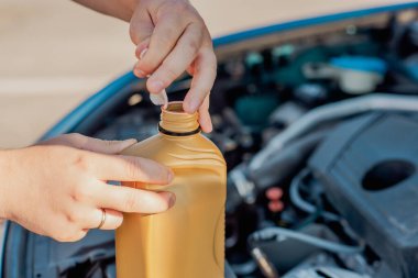 Bir arabanın motoruna motor yağı döken birinin yakın çekimi. Araç bakımı, yağ değişimi, otomotiv bakımı ve araba servisi kavramı.